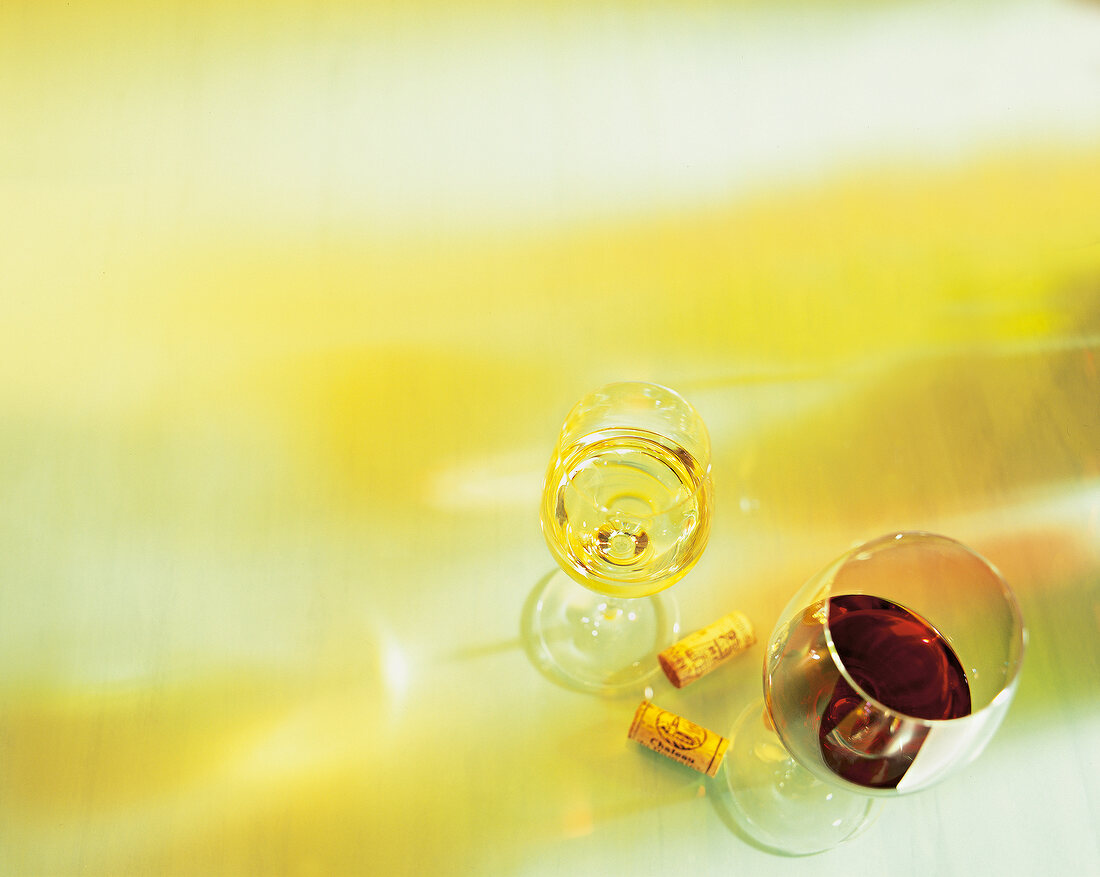 Two wine glasses and corks on yellow background