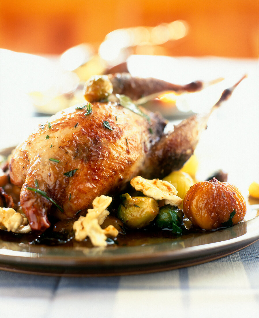 Close-up of roast partridge with pearl onions, nuts, grapes and Brussels sprouts on plate