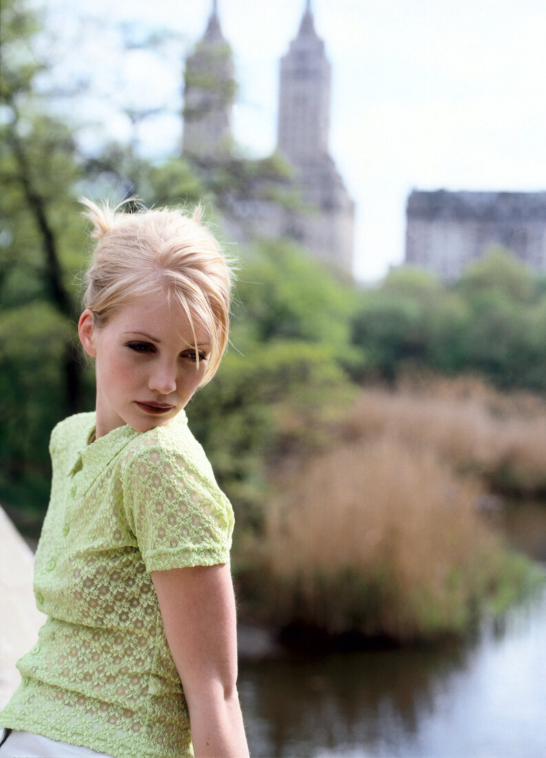 Glamorous blonde woman wearing green top and heavy make-up, looking away