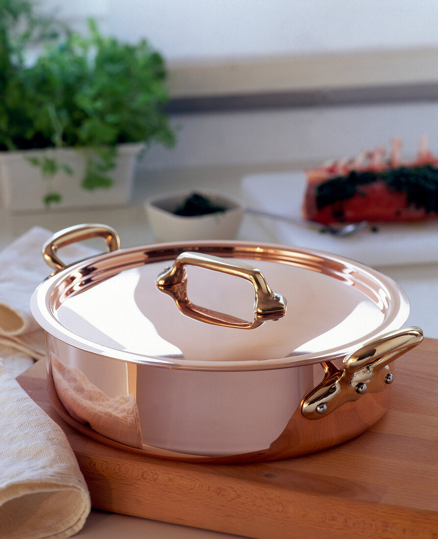 Copper pot for frying on wooden board