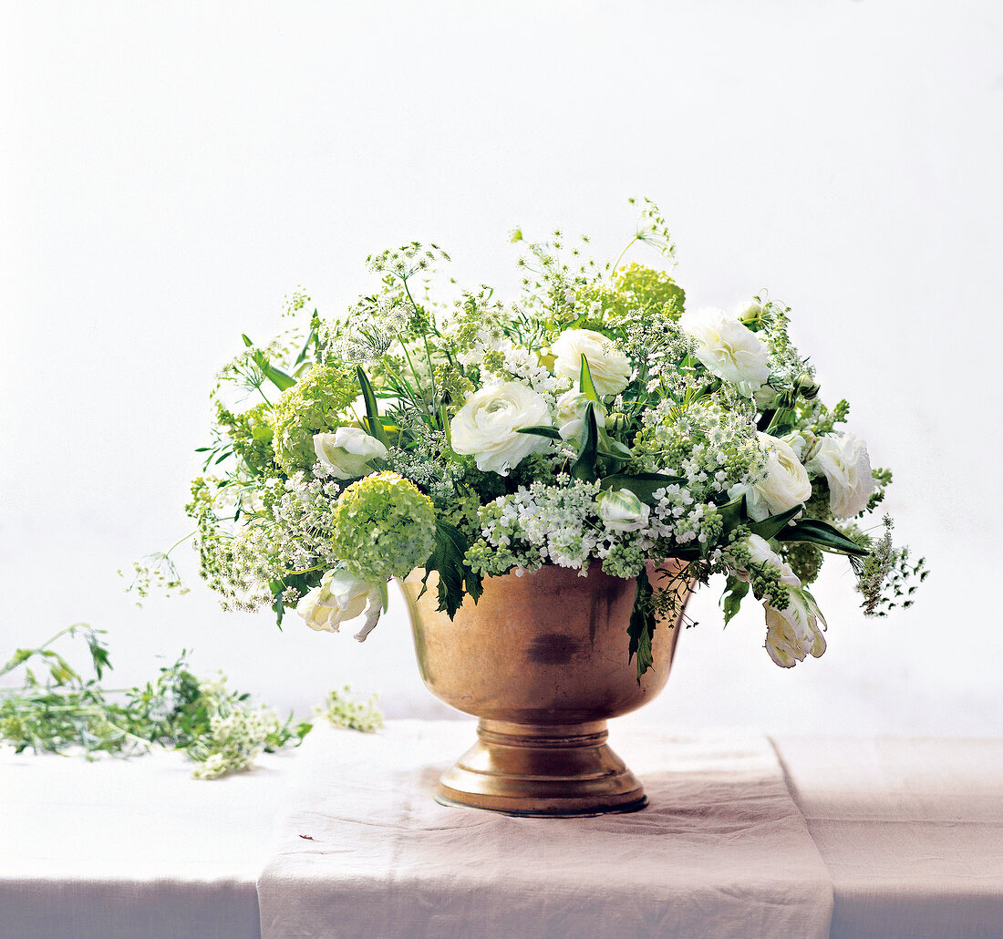 weiße und grüne Frühlingsblumen in einem Sektkübel