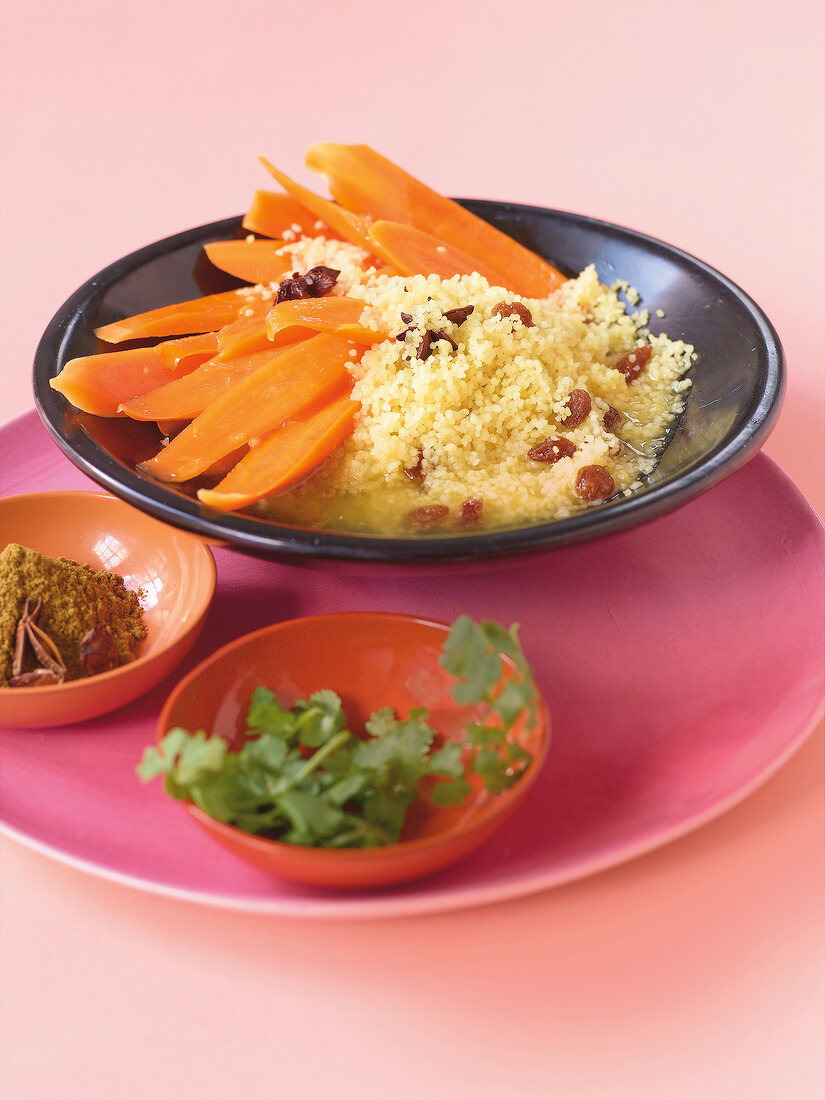 Orange and honey carrots with couscous, raisins and star anise in bowl