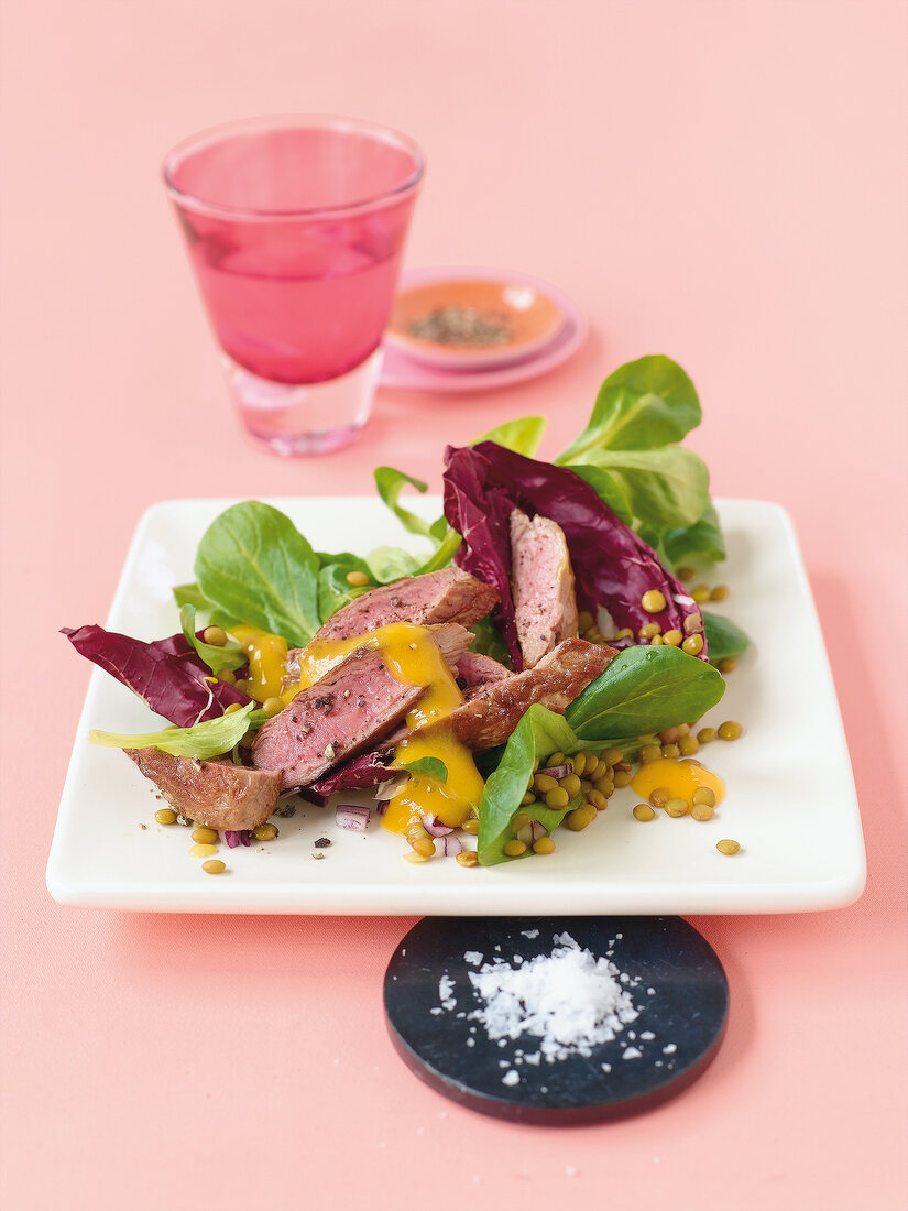 Lamb fillet with radish and lentil salad on square plate