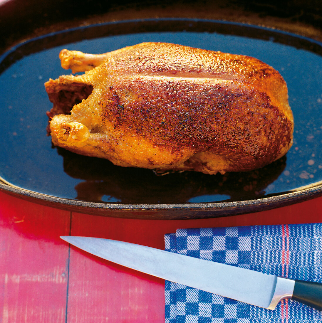 Roasted crispy muscovy duck on hearth plate with a knife on napkin