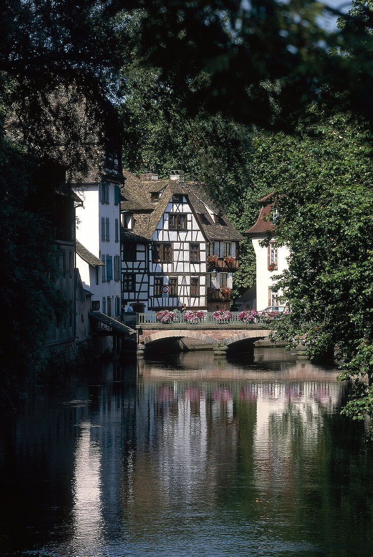 Half timbered houses and reflection in front of bridge in water, Strasbourg, France