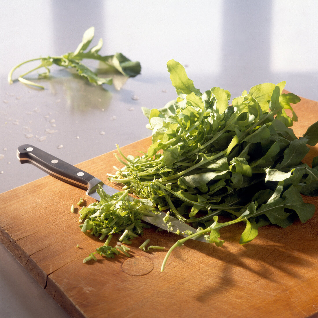 The lower thick stalks of fresh rocket cut on wooden cutting board