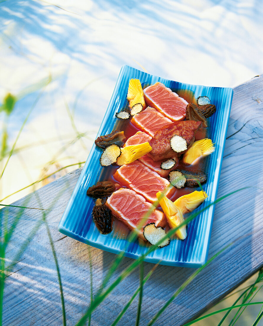 Lachsfilets mit Artischocken und Morcheln, auf blauer Servierplatte