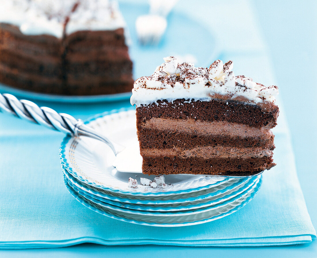 ein Stück Cappuccino-Torte auf Tortenheber und gestapelten Tellern