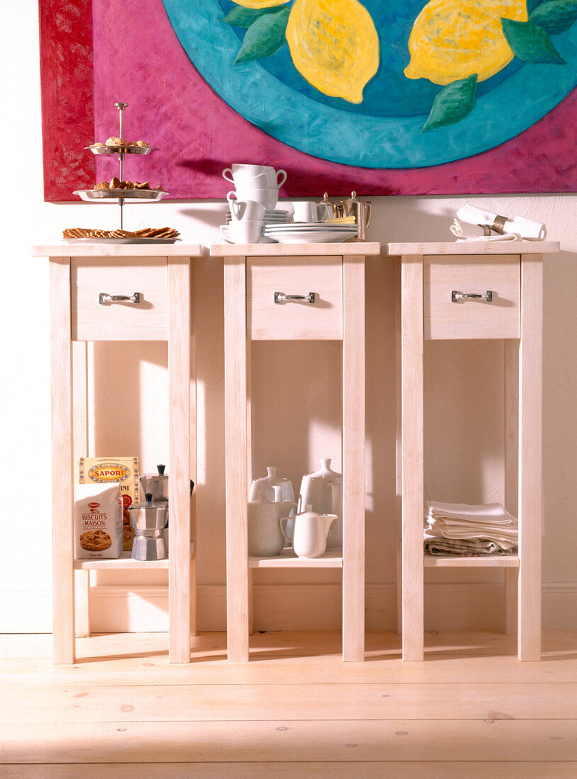 Close-up of pink table with drawers, cake stand, cup, plate and teapot