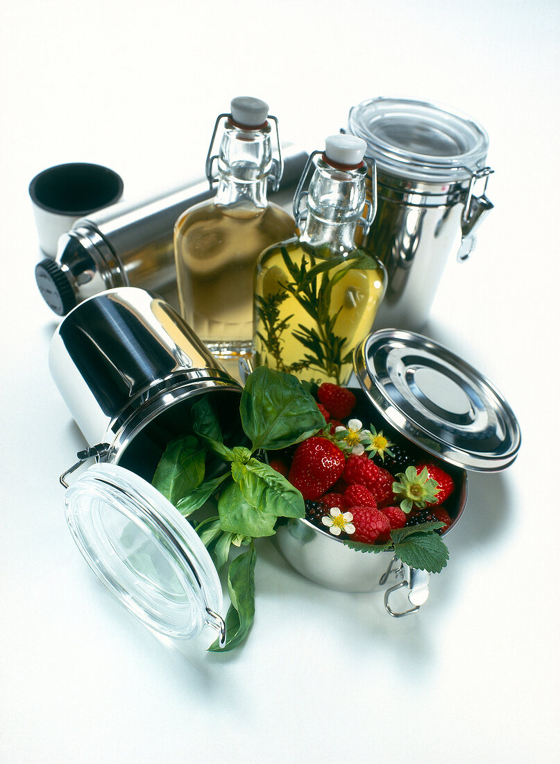Stainless steel box containers with berry fruits and two bottles on white background