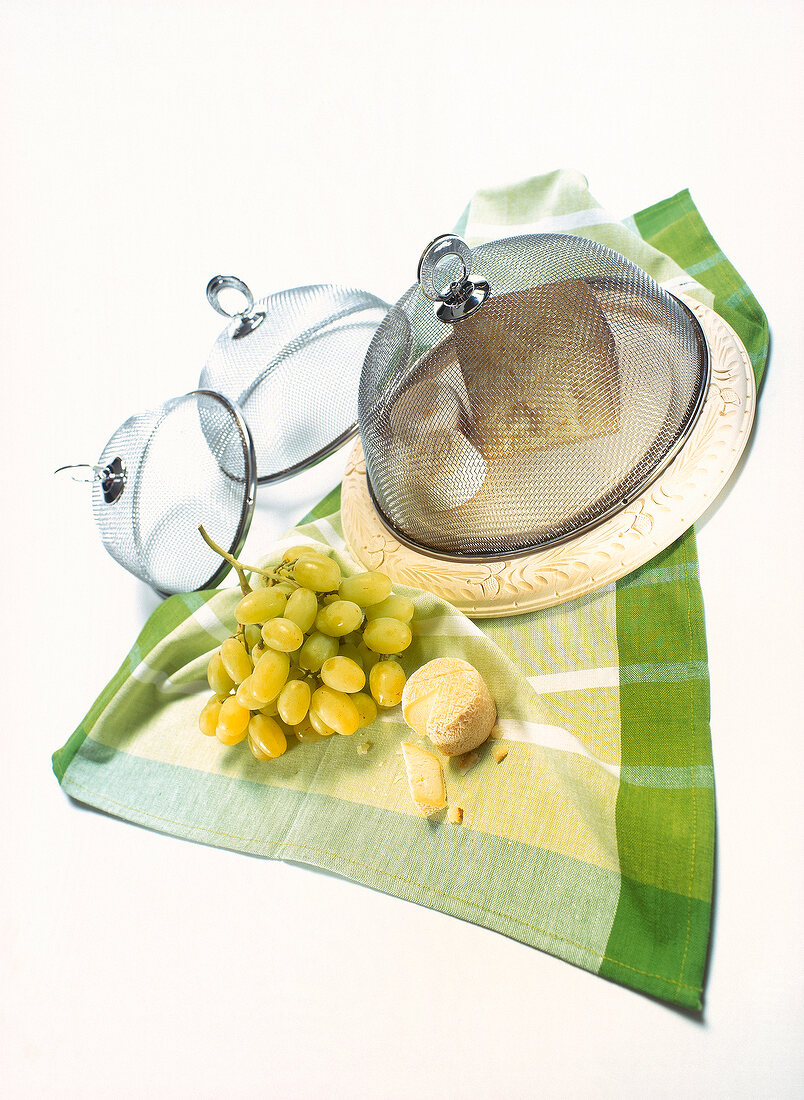 Three mesh dome cover, bunch of grapes and cheese on tea towel
