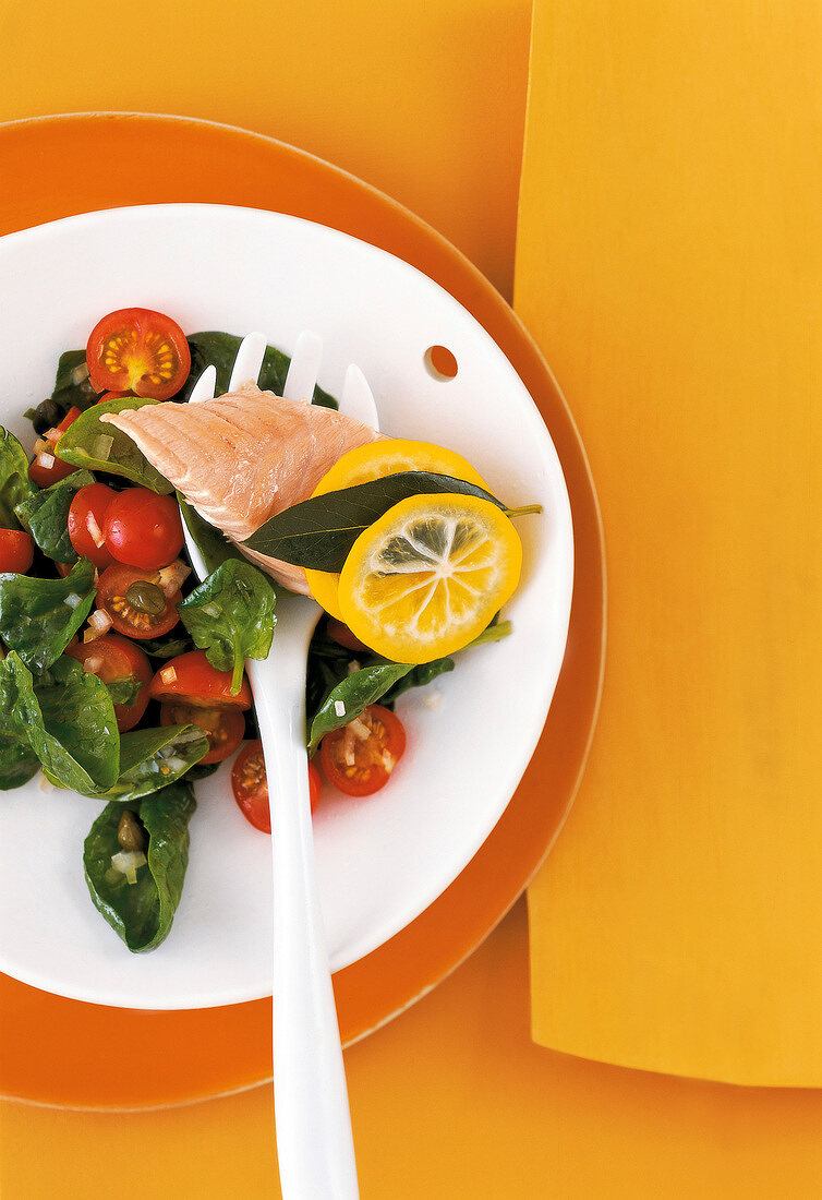 Spinach salad with tomato and salmon fillet on plate
