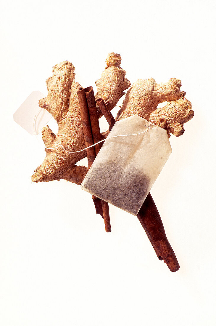 Ayurvedic tea bag tea with ginger root and cinnamon sticks on white background