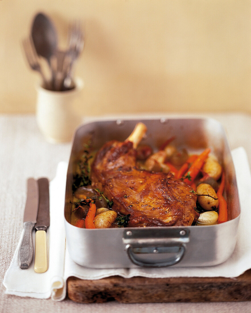 Suckling lamb with potatoes and carrots in roasting pan