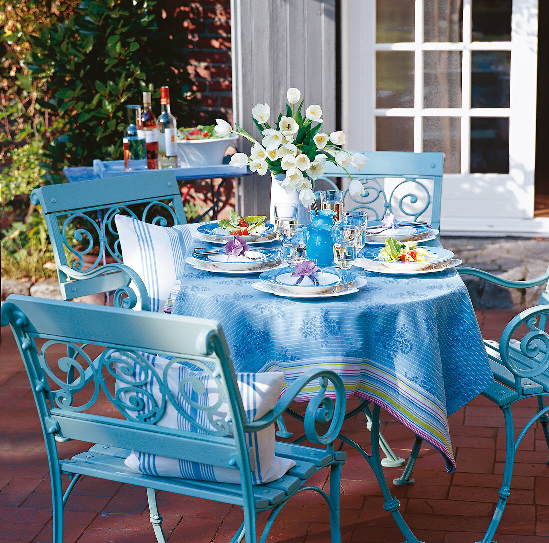 sommerlich gedeckter Tisch in blau auf einer Terrasse im Garten