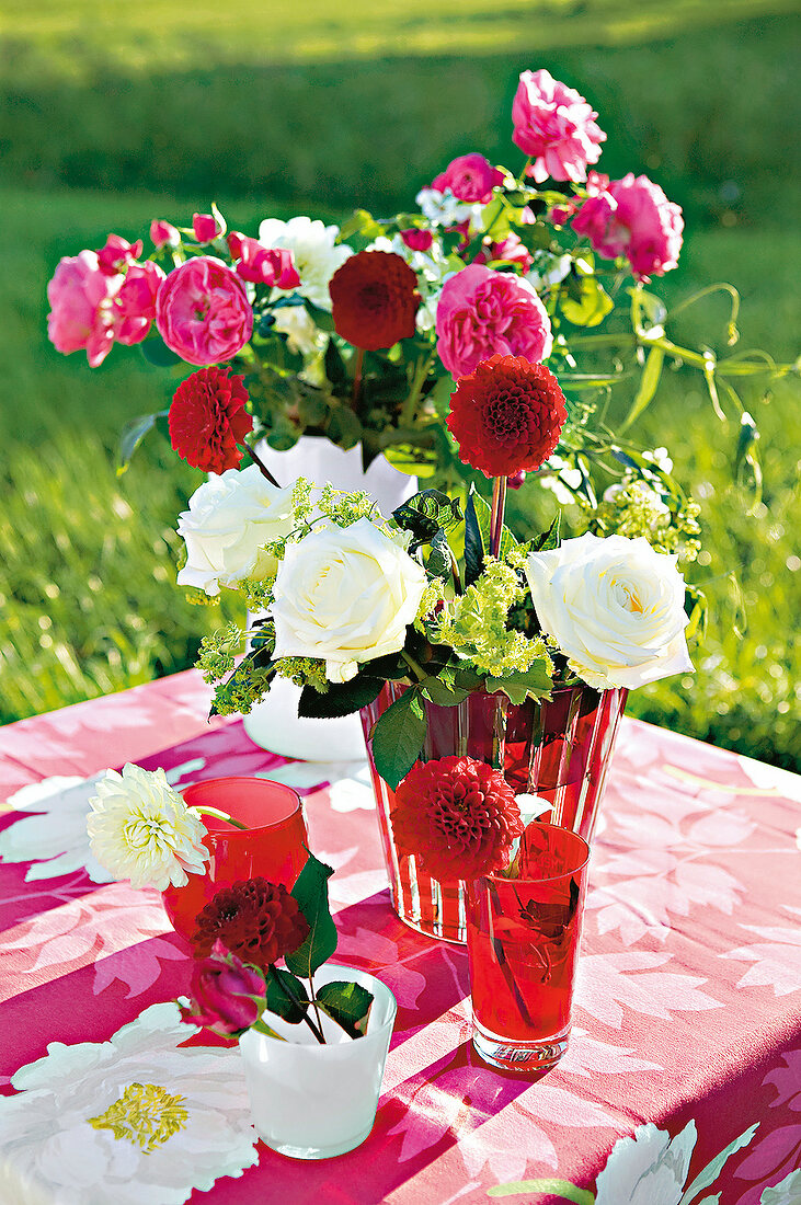 Strauß mit Rosen und Dahlien in Vase auf Tisch im Garten, Sommer