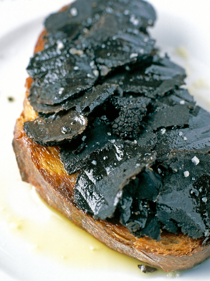 Bread with truffle slices on plate and glass of white wine