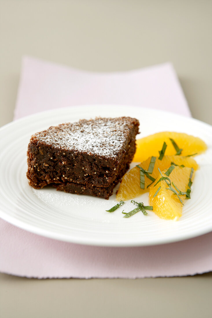 Ein Stück Schokoladen-Amarant-Kuchen dazu Orangenstücke