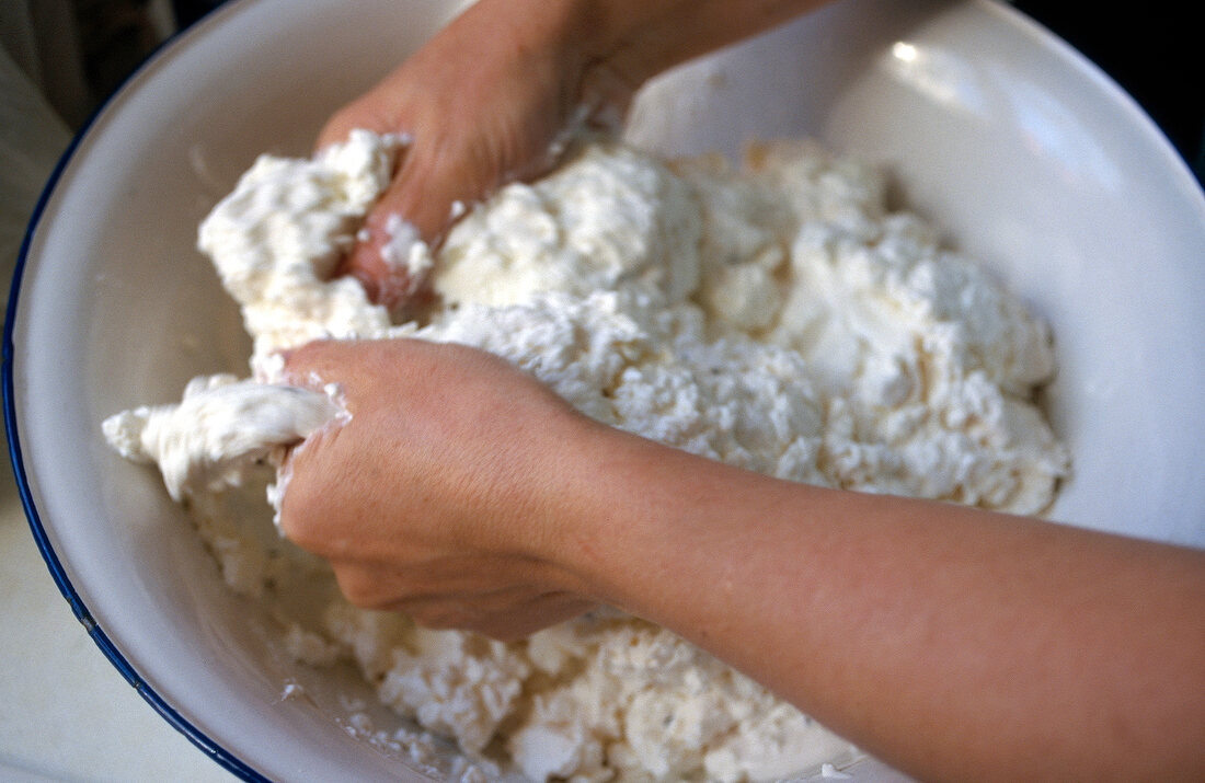 Close-up of man collecting curds for production of cheese