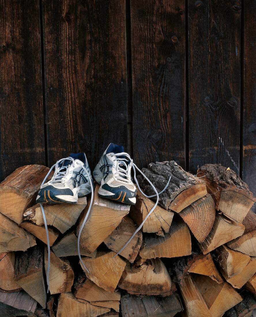 Paar Sportschuhe auf einem Haufen Brennholz