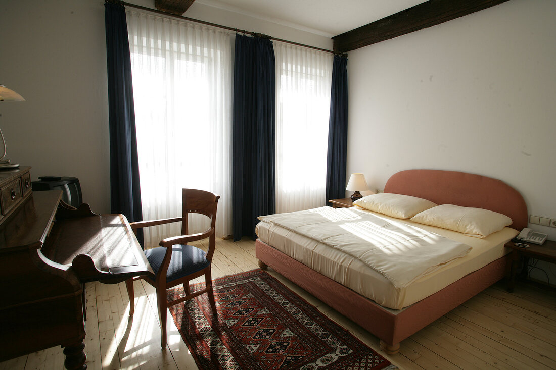 Bedroom with bed, chair and table in hotel, Germany