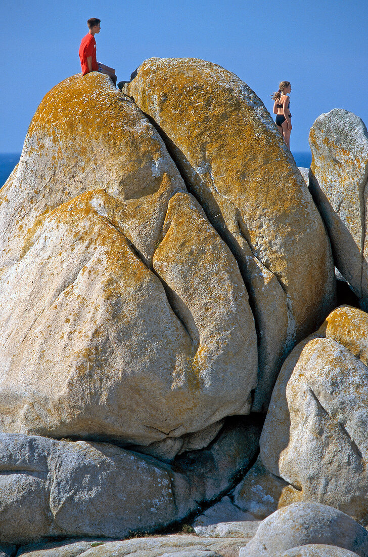 Zwei Urlauber an einem großen Felsen an der Küste der Bretagne