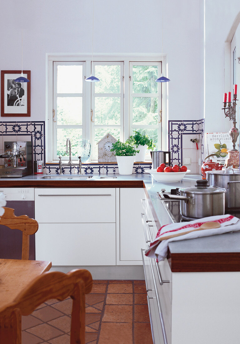 weiße Küche mit dunklen Bodenfliesen und blau-weißen Wandfliesen