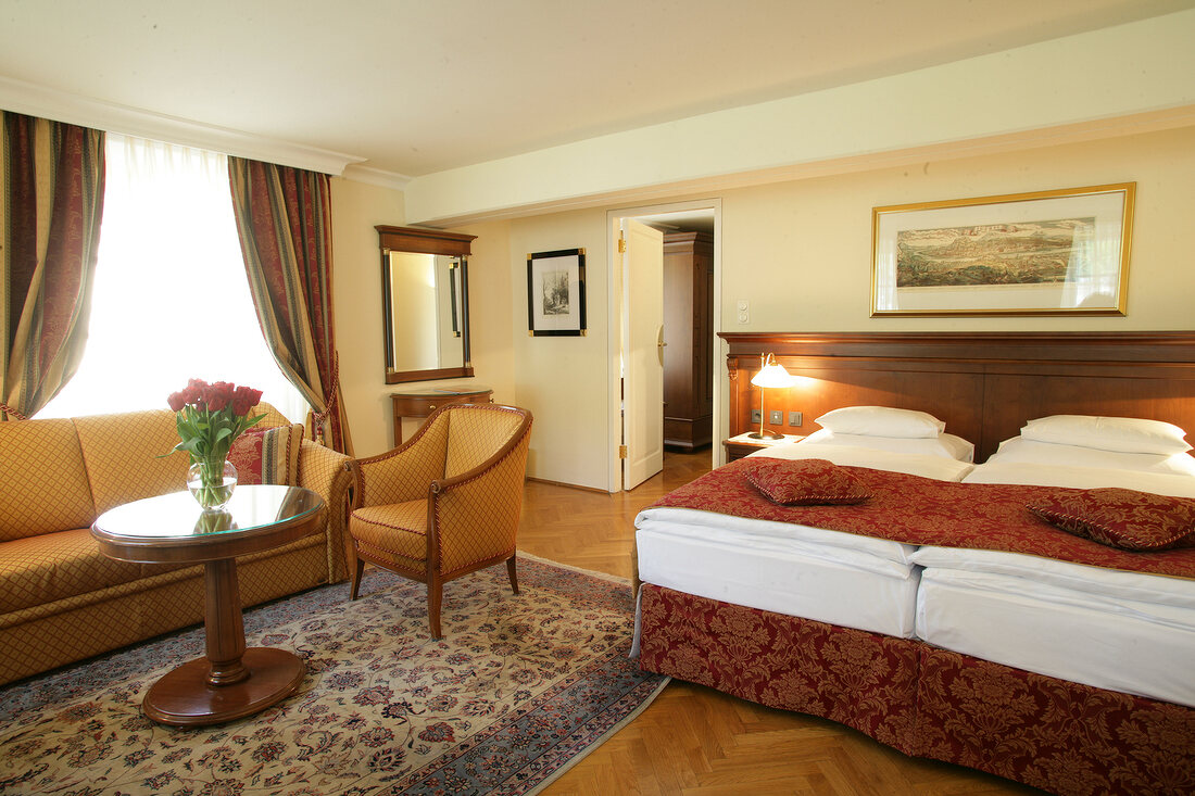 Interior view of hotel's bedroom with double bed, chair and sofa, Austria