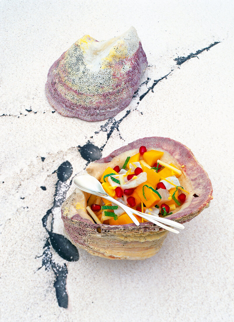 Raw marinated sea bass with mango and pomegranate in serving dish