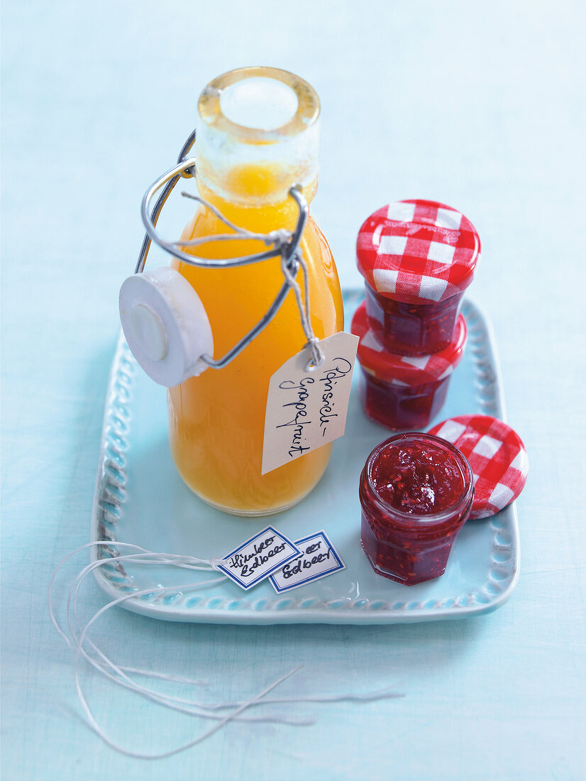 Flasche mit Pfirsich-Grapefruit-Sauce daneben Himbeer-Erdbeer-Konfitüre