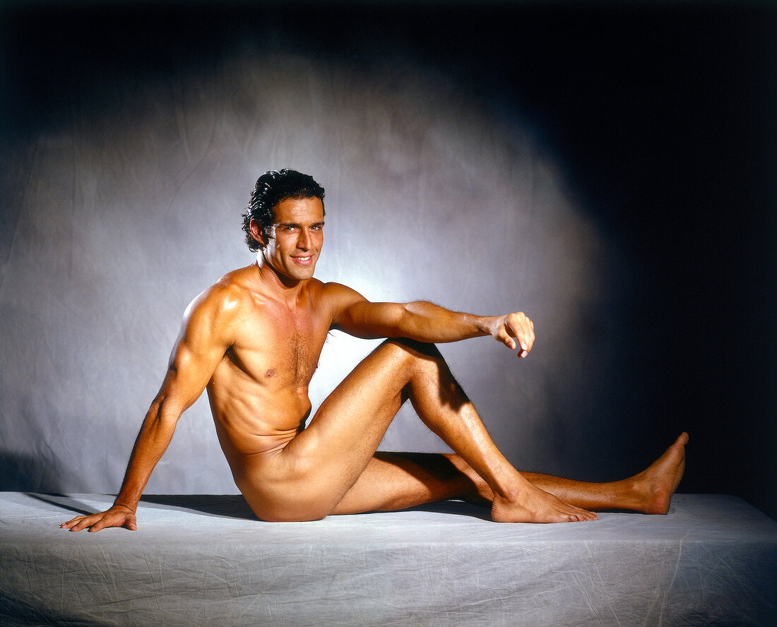 Portrait of handsome naked man sitting and smiling on floor, vignette