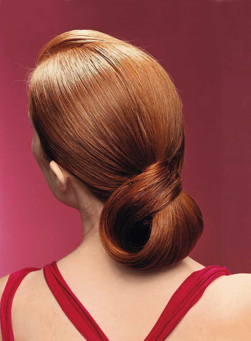 Rear view of red haired woman with hair loop against pink background