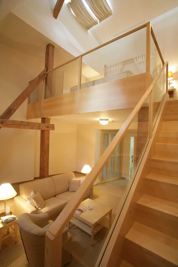 Wooden staircase with glass railings and creme sofa at hotel in Czech Republic