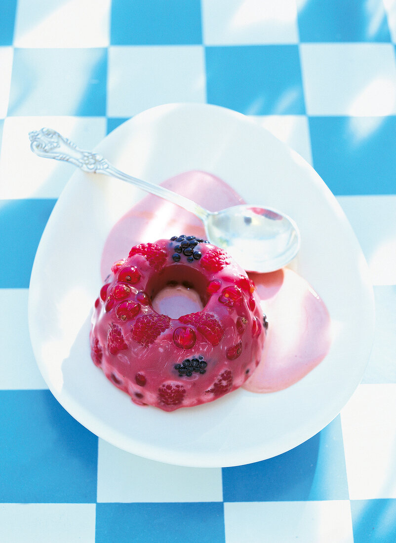 Red fruit jelly with cream sauce on plate