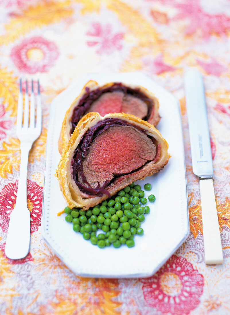 Fillet of beef with red onions and green peas served on plate