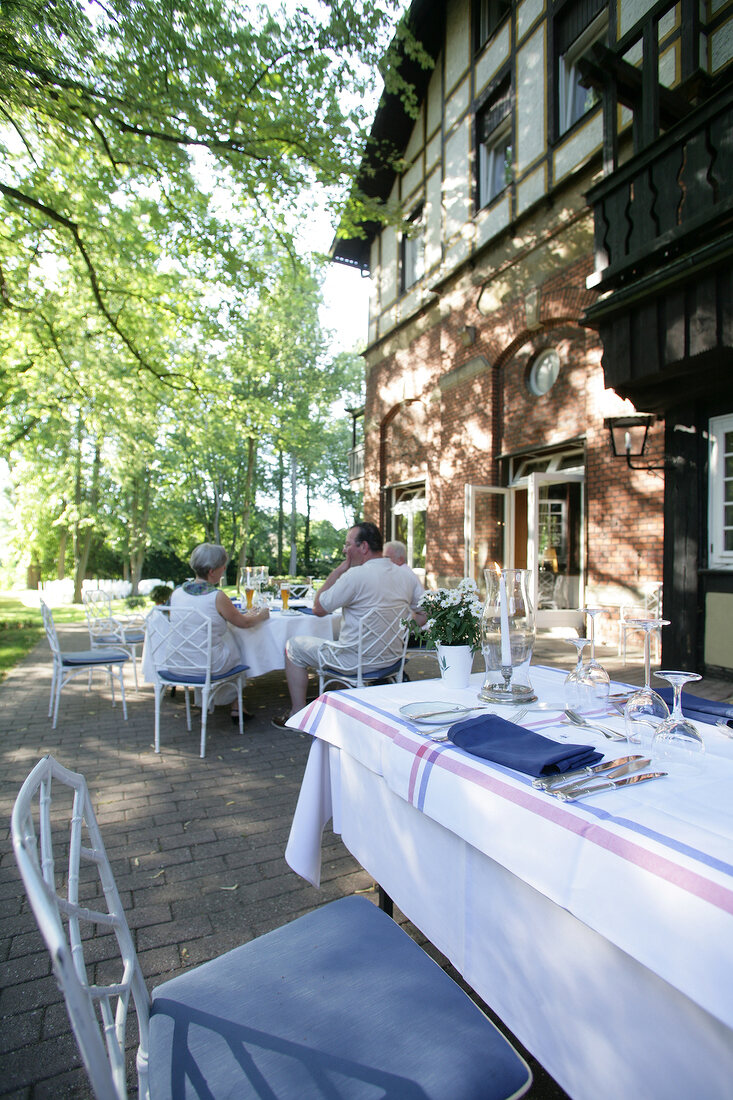 People sitting at table outside hotel, Germany