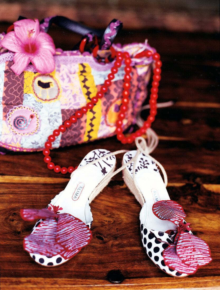 Sandals decorated with jungle flower and handbag on wood