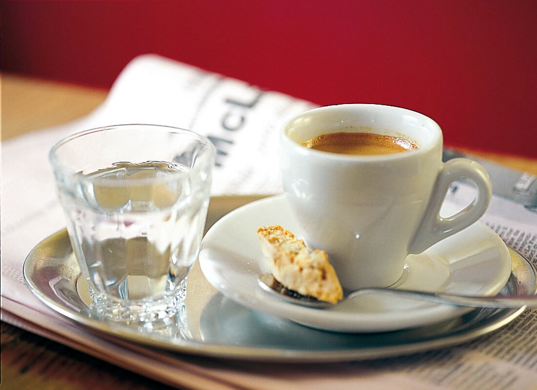 Espresso und Glas Wasser auf einem silbernen Tablett