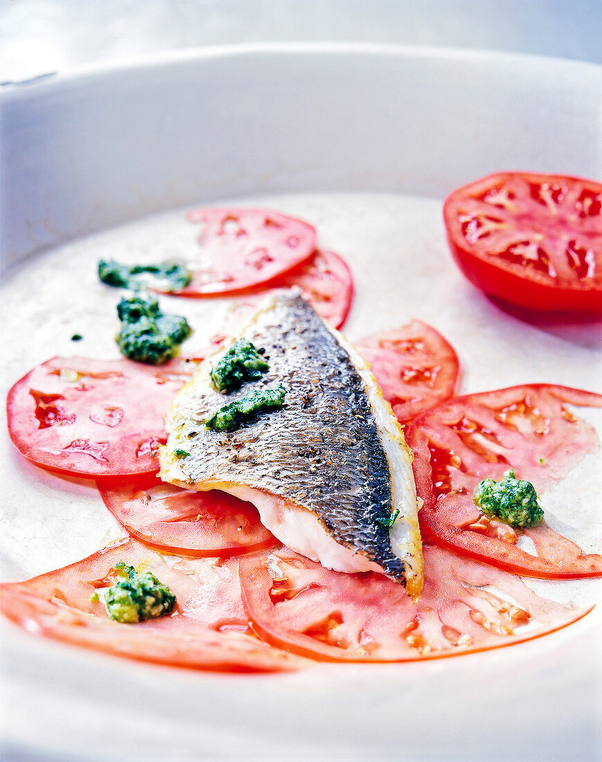 Close-up of tomatoes Carpaccio with fried sea bream and rocket pesto