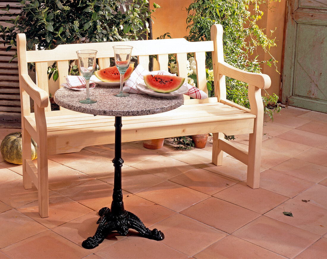 Garden bench made of untreated spruce wood with bistro table in garden