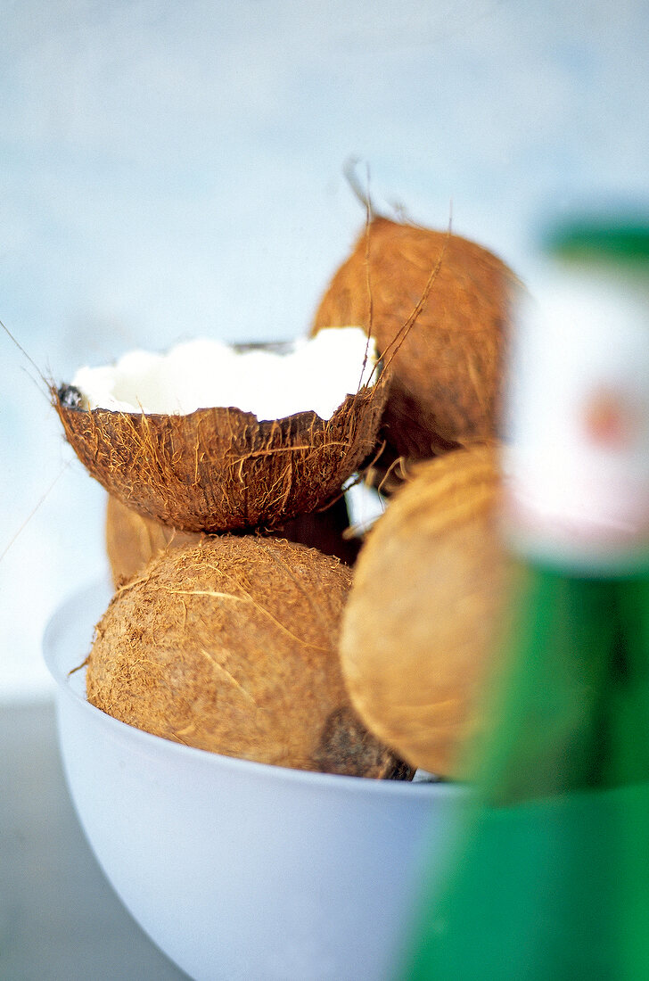 Halved and whole coconuts in gray bowl