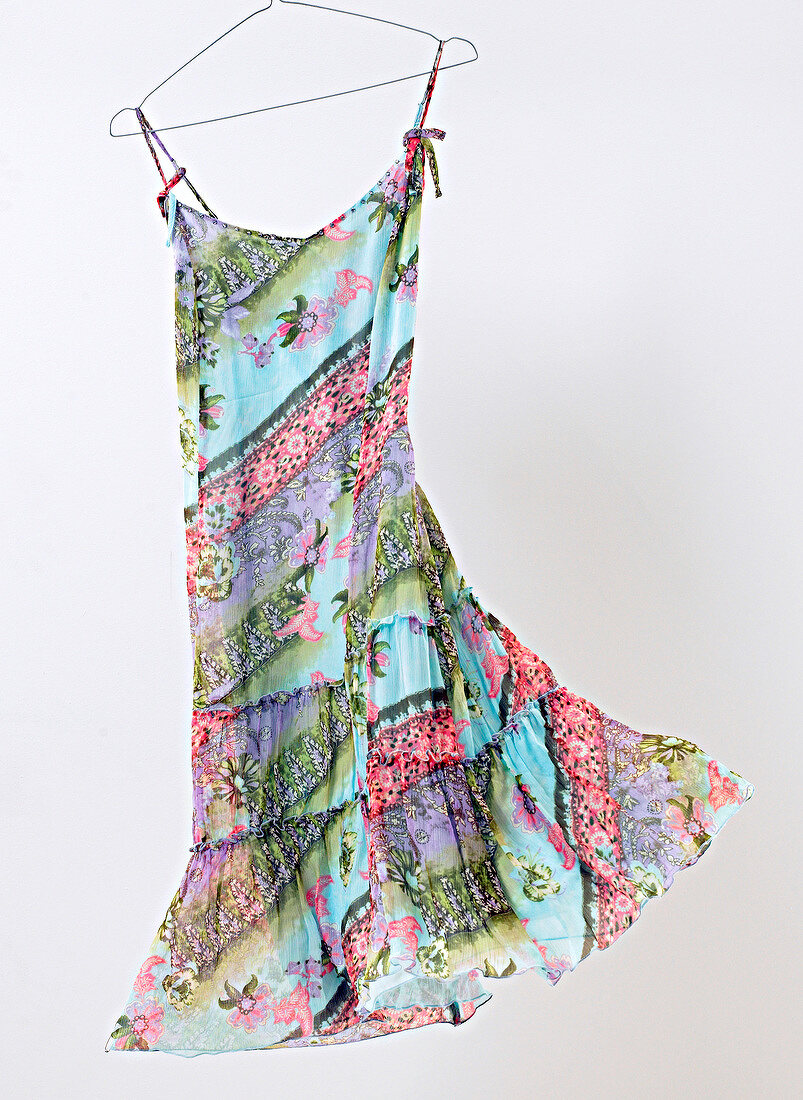 Blue-green silk sundress hanging on coat hanger