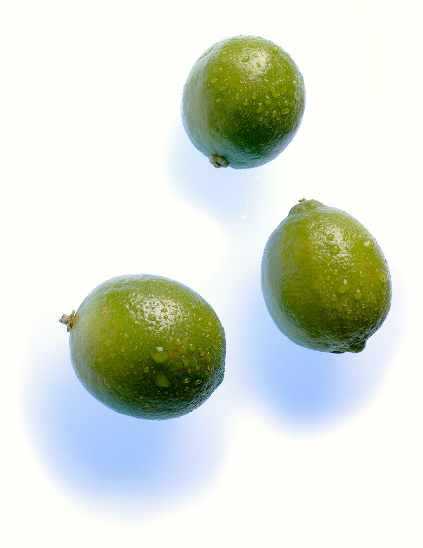 Close-up of three green lemon on white background