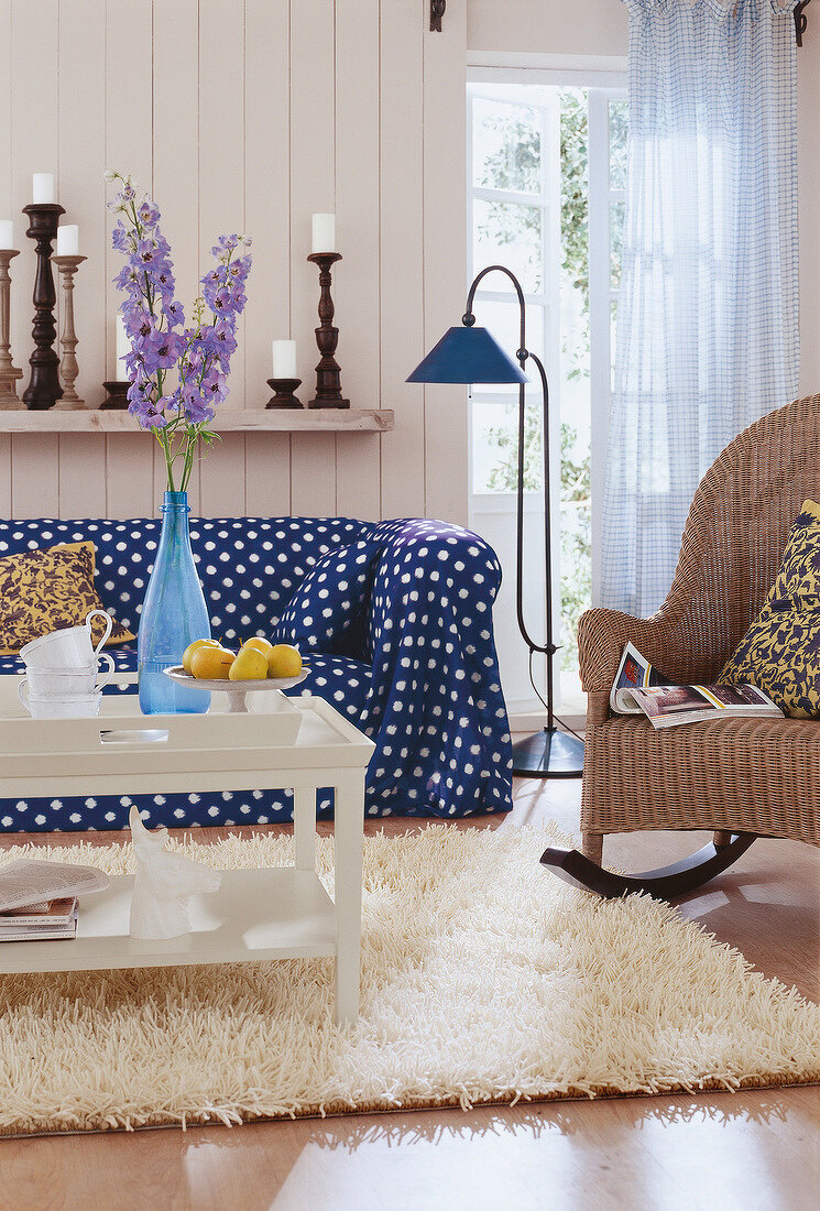 Zimmer mit Korbschaukelstuhl, Sofa und Couchtisch, flauschiger Teppich