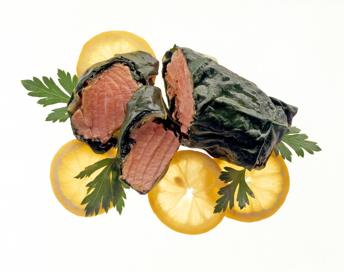 Close-up of salmon wrapped in Swiss chard with slices of lemon and thyme