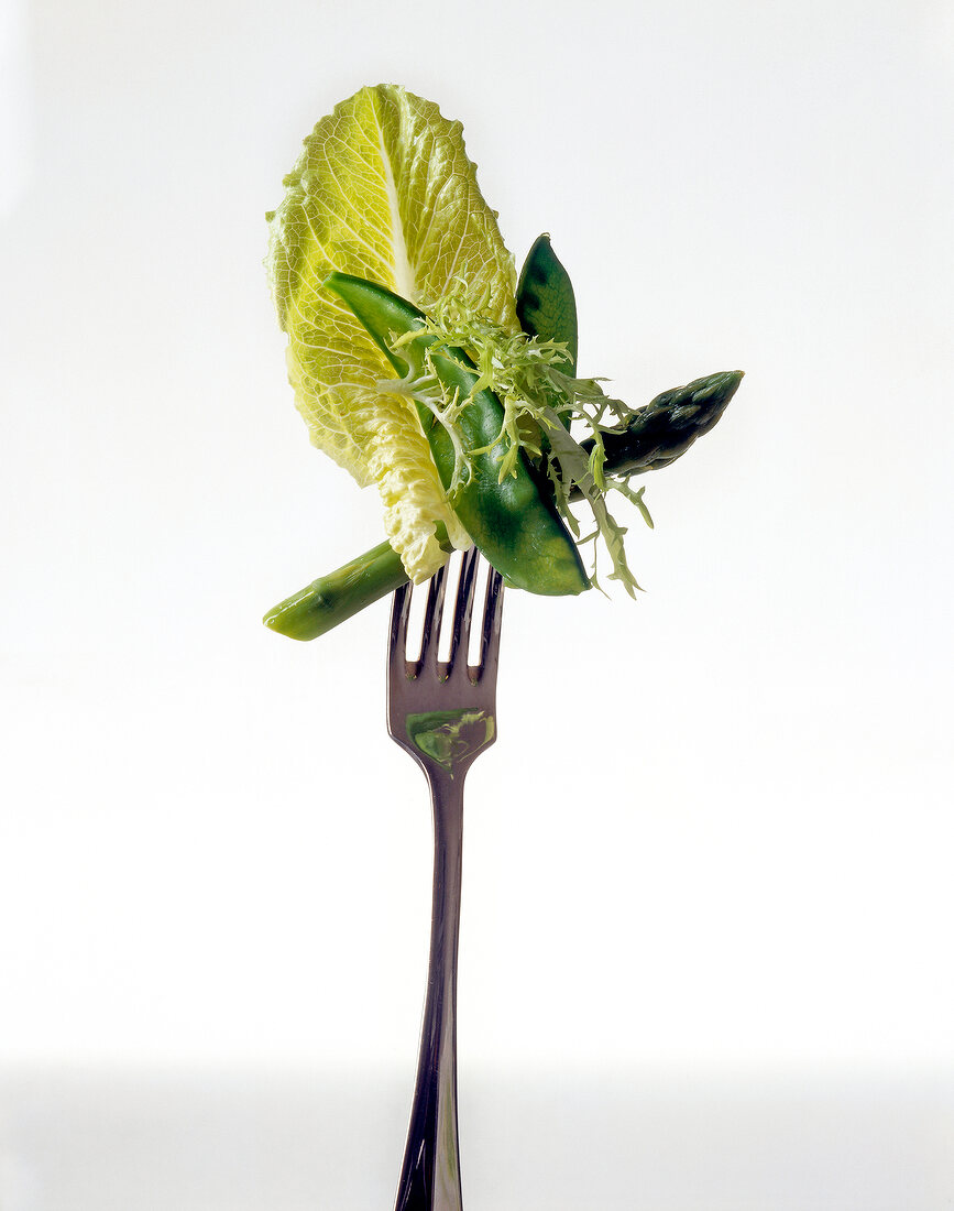 Close-up of green asparagus and cabbage leaf on fork