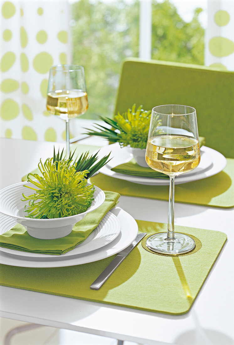 Bowl with green flowers and glass of white wine on table