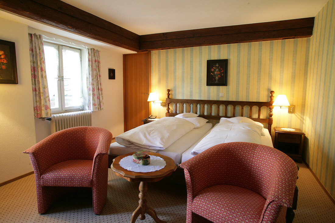 Bedroom with bed, cushion, chairs and lamp in hotel, Germany