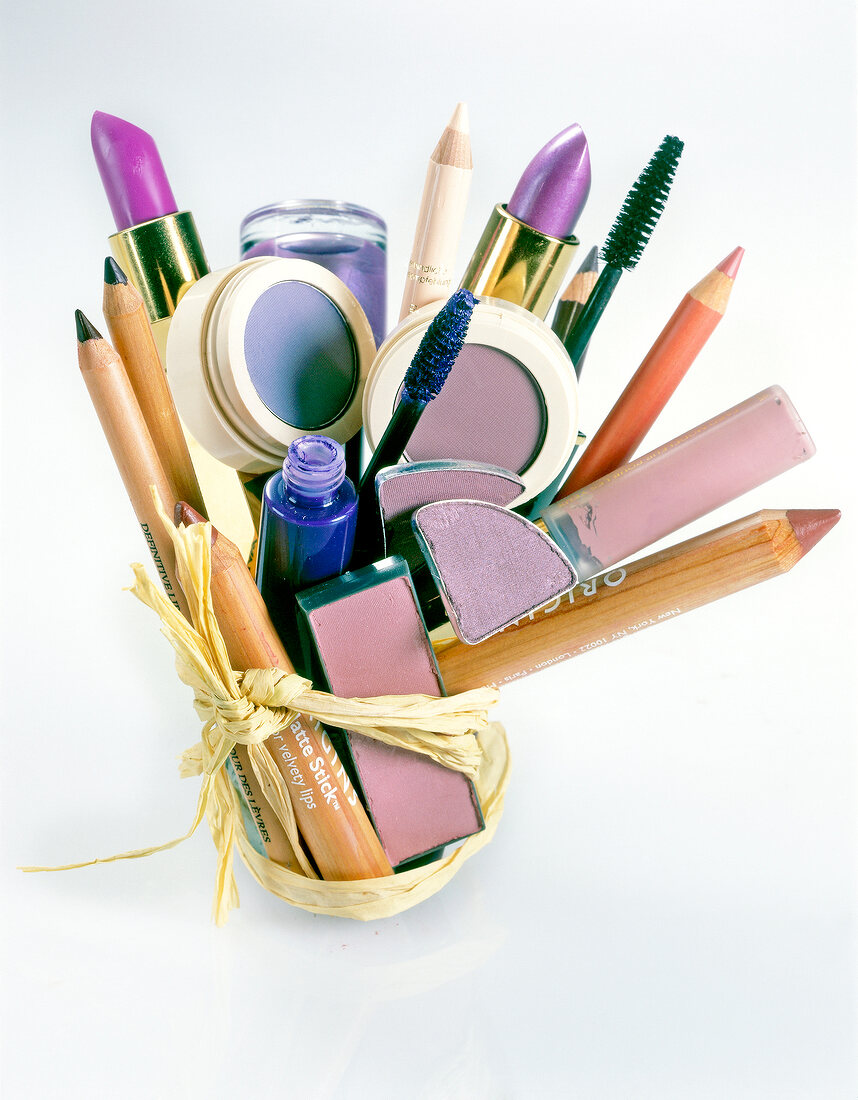 Various beauty products tied together with a ribbon on white background