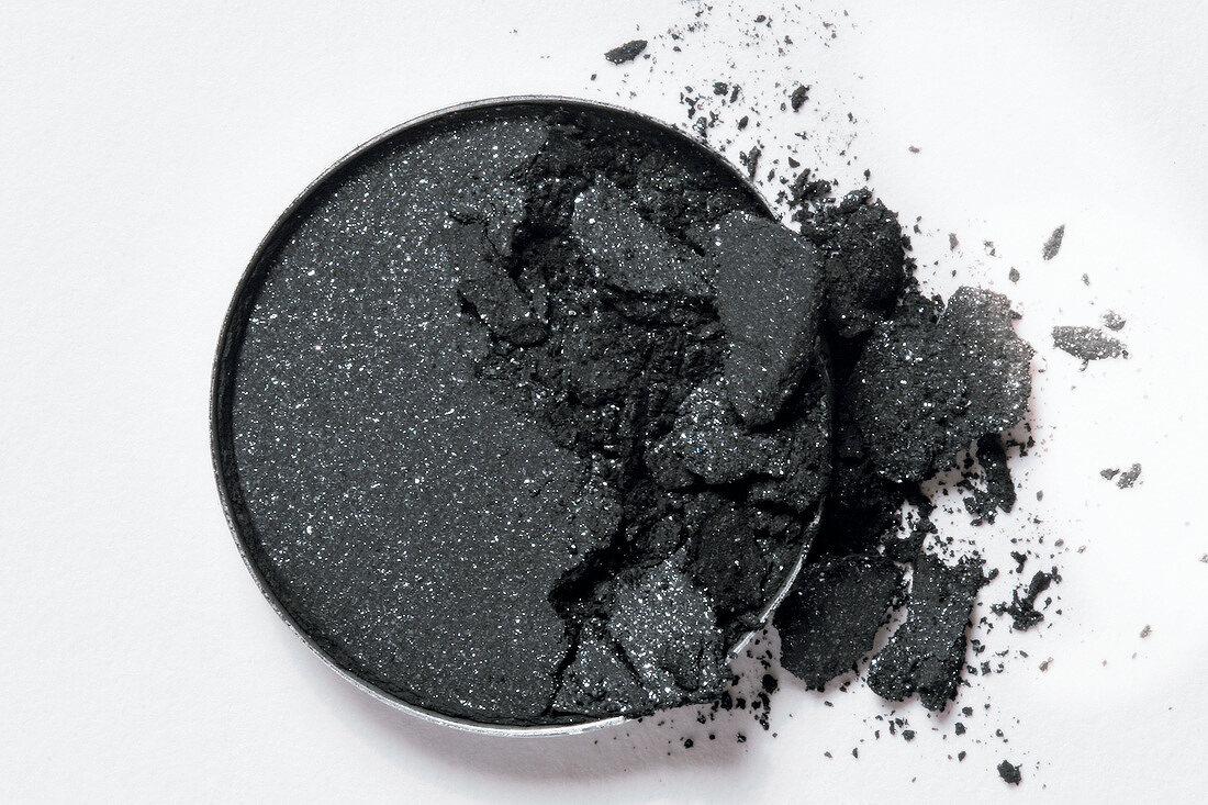 Close-up of broken gray eye shadow on white background